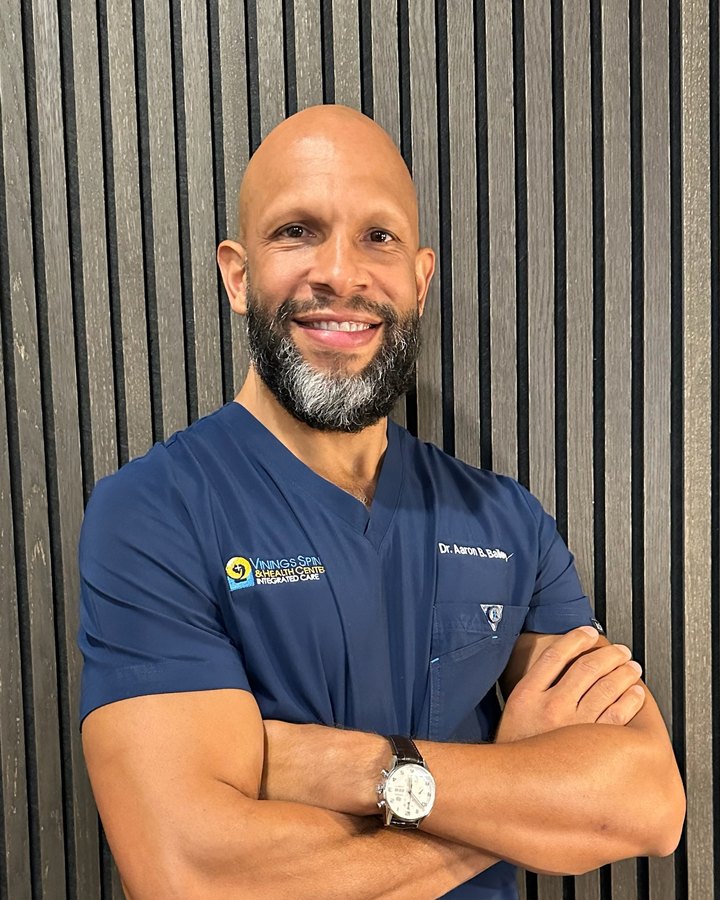 Dr. Aaron Bailey, DC, smiling in navy scrubs at Vinings Spine & Health Center